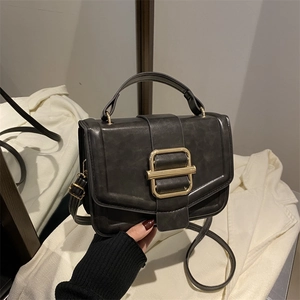 Détail de la texture cuir noir vintage avec boucle dorée sur un sac à main élégant