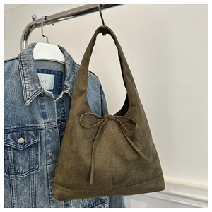 Detail of a vintage green suede tote bag featuring a decorative bow tie and soft texture