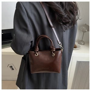 Détail d'un sac seau vintage marron foncé avec double poignée et texte mode embossé