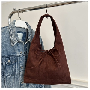 Detail of dark brown suede tote bag featuring a decorative ribbon bow and sturdy base