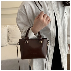Détail du sac seau marron foncé avec gaufrage FASHION et anneaux métalliques dorés