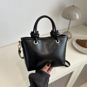 Détail du sac bandoulière en cuir noir mat avec lettrage FASHION et ferrures dorées