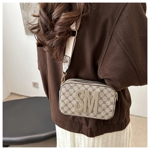 Detail view of small beige monogram crossbody bag with wide strap and SM logo