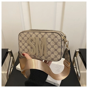 Detail view of monogram canvas camera bag with gold zipper and wide woven strap
