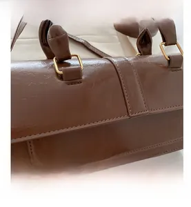 Detail of brown PU leather bag showing golden metal buckles and pleated texture