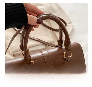 Close-up of vintage brown leather handbag with textured pleats and golden metal hardware