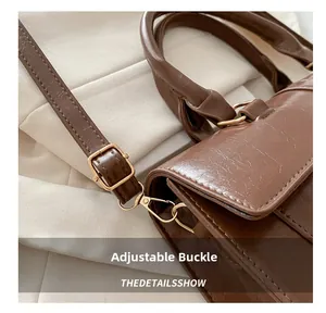 Detail of adjustable golden buckle and retro oil wax leather texture on brown handbag