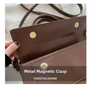 Macro detail of golden magnetic buckles and brown faux leather texture on crossbody bag