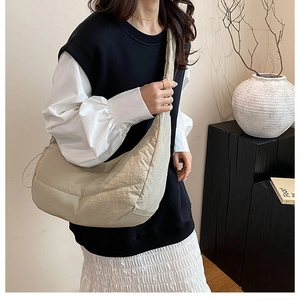 Detalle del bolso de hombro plisado beige con cordón sobre un fondo de estudio minimalista