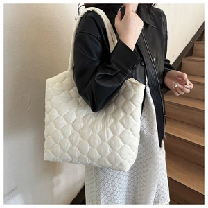 White quilted puffer tote bag shown on shoulder in a stylish minimalist setting