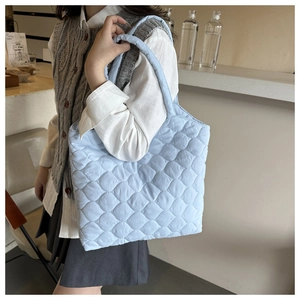 Detail of light blue quilted tote bag with diamond stitching and soft puffy texture