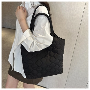 Detail of black quilted tote bag showing wave stitching texture on shoulder
