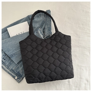 Detailed view of black quilted tote bag texture with soft nylon padding and stitching