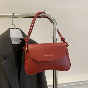 Detail of dark red flap bag featuring knotted strap and golden Fashion & Bags logo