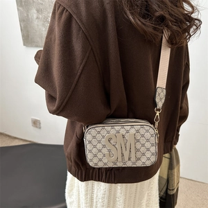 Vintage brown monogram crossbody bag with large SM logo and adjustable strap worn by model
