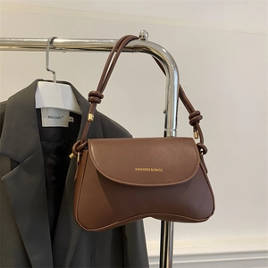 Detail of brown PU leather flap bag with gold FASHION & BAGS logo and sleek curved base