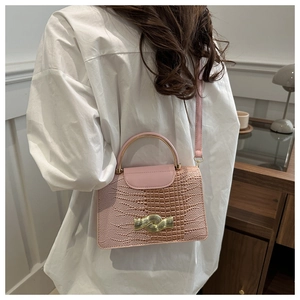 Détail du sac rose effet crocodile avec poignée métallique et fermoir doré chic