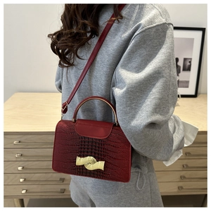 Texture détaillée du sac bordeaux en cuir gaufré crocodile avec poignée en métal doré