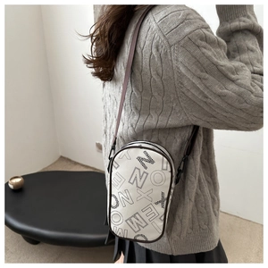 Detail of printed crossbody phone bag with wide strap on model wearing knit sweater