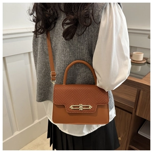 Detail of brown leather crossbody bag with snake-skin texture flap and gold buckle