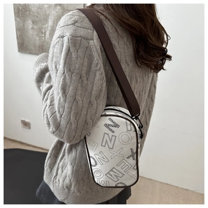 White PU crossbody bag with black letter print and brown wide strap on a model