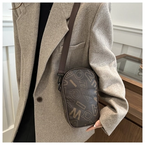 Detail of a dark brown crossbody phone bag with vintage letter patterns on a model