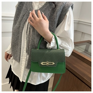 Detail of green textured leather handbag featuring a snakeskin pattern and gold buckle