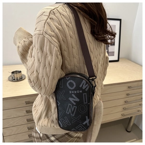 Detail of trendy HORHE crossbody bag with white letter patterns on black textured leather