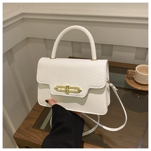Detail of white crocodile pattern flap and golden metal lock on stylish handbag