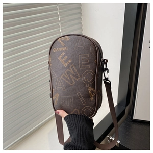 Detailed view of vintage brown leather phone bag with letter prints and adjustable strap