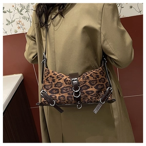 Détail d'un sac bandoulière léopard avec boucles argentées et finitions en cuir sur mannequin
