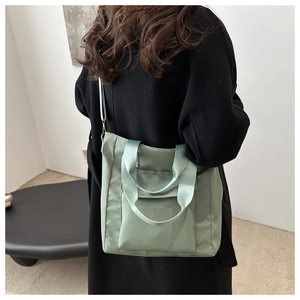 Detail of light green water-resistant nylon tote bag with dual handles and long strap
