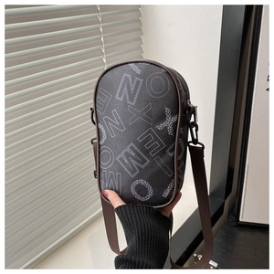 Detail of a black crossbody bag with white letters, brown leather trim, and canvas strap