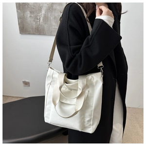 Detailed view of white nylon tote bag with adjustable shoulder strap on a model