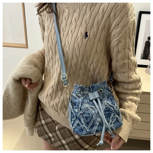 Close-up of quilted denim bucket bag with frayed edges and drawstring closure