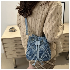 Detail of blue denim bucket bag with frayed quilted pattern and drawstring closure