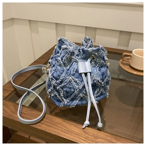Close-up of blue denim bucket bag with quilted frayed edges and drawstring closure
