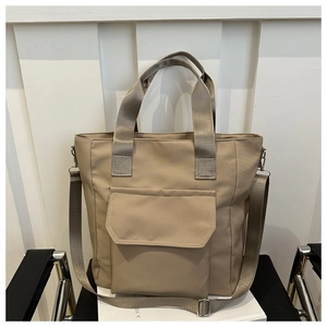 Detail of khaki nylon tote bag showing double handles, stitching, and front flap pocket
