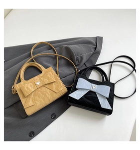 Detailed close-up of bow handbags with heart rhinestones in beige and black variants