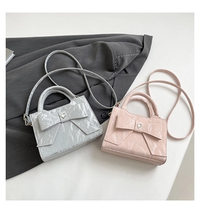 Close-up of heart crystal and bow detail on wrinkled patent leather handbag