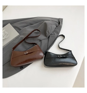 Detail of minimalist leather shoulder bags in brown and black with buckle accents