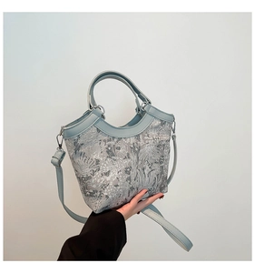 Detail of floral embroidery on light blue silk and leather crossbody bucket bag