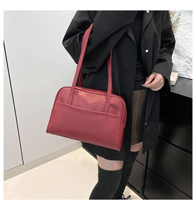 Macro view of dark red PU leather shoulder bag with fine texture and front pocket detail