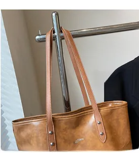Close-up of caramel brown leather tote bag with vintage texture and stylish silver rivets