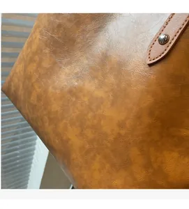 Macro detail of brown leather tote showing fine stitching and silver rivets texture