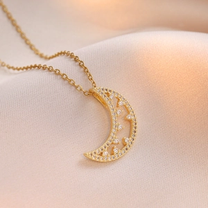 Elegant gold crescent moon pendant necklace with sparkling zircons on satin background