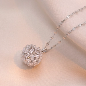 Exquisite hollow sphere pendant necklace with cubic zirconia on pink silk background