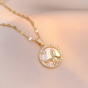 Golden rabbit necklace with zircon circle pendant on champagne satin background