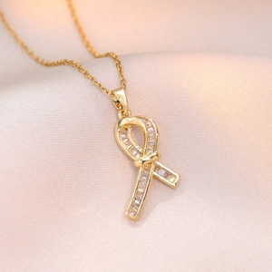 Elegante collana a fiocco dorata con pendente in zircone su velluto beige