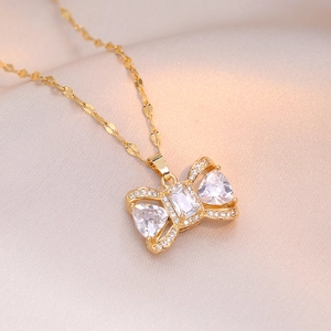 Elegant gold bow necklace with sparkling zircon pendant on soft silk background